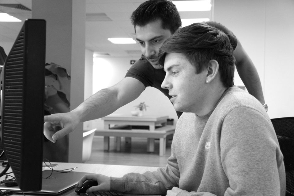 two young men looking at a computer screen
