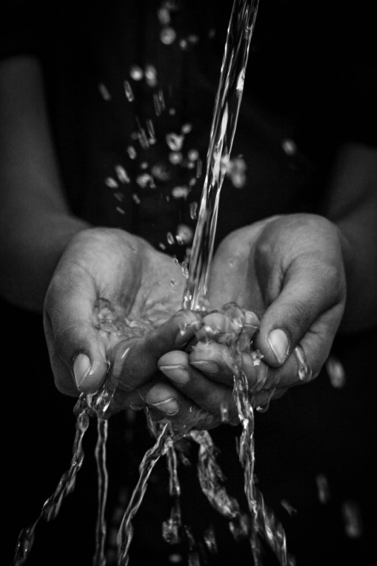 a woman's hands with water pouring over them